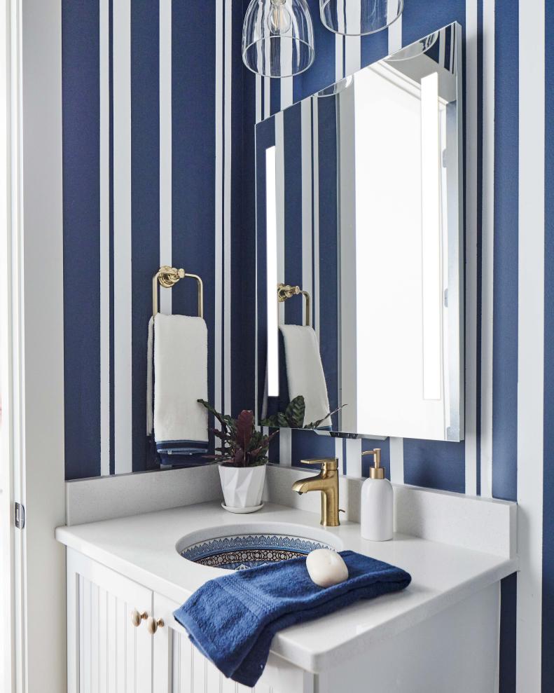 With bold striped walls and user-friendly features, this powder room located on the first floor of HGTV Smart Home 2022 reflects the contemporary style of this sophisticated and timeless waterside retreat.